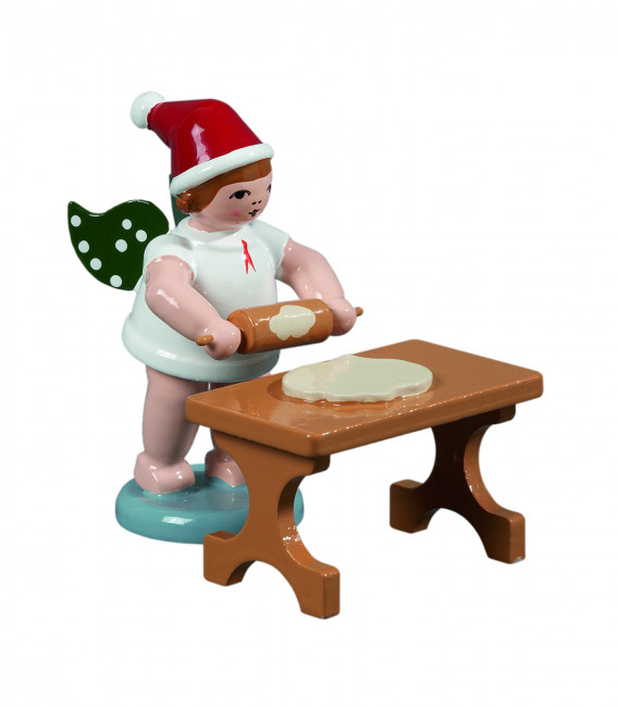 Weihnachtsengel mit Teigrolle am Tisch mit Mütze