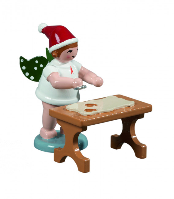 Weihnachtsengel mit Ausstechform am Tisch mit Mütze