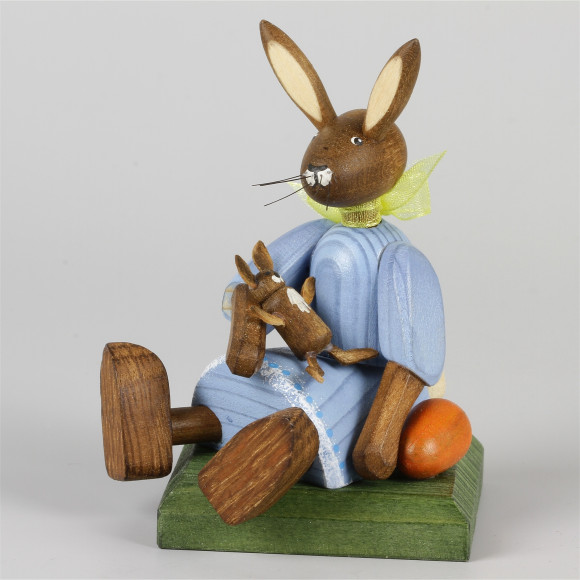Kleines Hasenmädchen mit Puppe, sitzend, blau