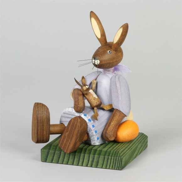 Kleines Hasenmädchen mit Puppe, sitzend, lila