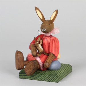 Kleines Hasenmädchen mit Puppe, sitzend, rot