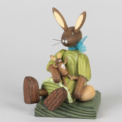 Kleines Hasenmädchen mit Puppe, sitzend, grün